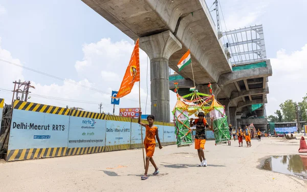 Gaziabad, Uttar Pradesh, Hindistan - 24 Temmuz 2022: Hindu hacı portresi Muson zamanında Lord Shiv 'e ibadet etmek ve nehir çetelerinin kutsal suyunu taşımak için çıplak ayakla kanwar yatra yapıyor.