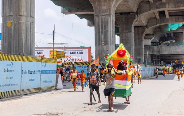 Gaziabad, Uttar Pradesh, Hindistan - 24 Temmuz 2022: Hindu hacı portresi Muson zamanında Lord Shiv 'e ibadet etmek ve nehir çetelerinin kutsal suyunu taşımak için çıplak ayakla kanwar yatra yapıyor.