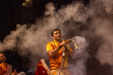 Varanasi, Uttar Pradesh, Hindistan - 20 Kasım 2022: Ganga aarti, Dashashwamedh ghat 'ında geleneksel Hint ayinleriyle akşam üzeri genç rahibin kutsal nehir çetelerini sergilediği portre.