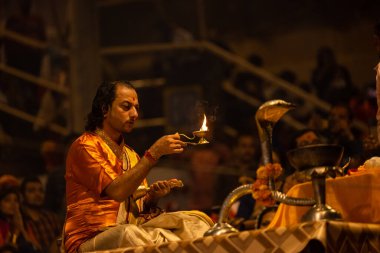 Varanasi, Uttar Pradesh, Hindistan - 20 Kasım 2022: Ganga aarti, Dashashwamedh ghat 'ında geleneksel Hint ayinleriyle akşam üzeri genç rahibin kutsal nehir çetelerini sergilediği portre.