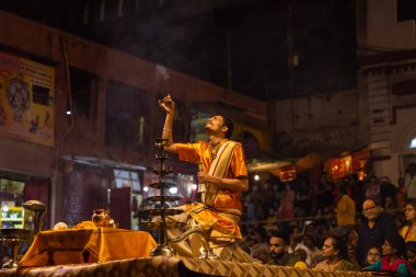 Varanasi, Uttar Pradesh, Hindistan - 20 Kasım 2022: Ganga aarti, Dashashwamedh ghat 'ında geleneksel Hint ayinleriyle akşam üzeri genç rahibin kutsal nehir çetelerini sergilediği portre.