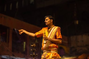 Varanasi, Uttar Pradesh, Hindistan - 20 Kasım 2022: Ganga aarti, Dashashwamedh ghat 'ında geleneksel Hint ayinleriyle akşam üzeri genç rahibin kutsal nehir çetelerini sergilediği portre.