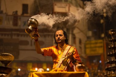 Varanasi, Uttar Pradesh, Hindistan - 20 Kasım 2022: Ganga aarti, Dashashwamedh ghat 'ında geleneksel Hint ayinleriyle akşam üzeri genç rahibin kutsal nehir çetelerini sergilediği portre.