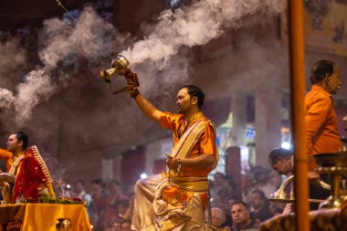 Varanasi, Uttar Pradesh, Hindistan - 20 Kasım 2022: Ganga aarti, Dashashwamedh ghat 'ında geleneksel Hint ayinleriyle akşam üzeri genç rahibin kutsal nehir çetelerini sergilediği portre.