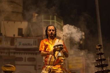 Varanasi, Uttar Pradesh, Hindistan - 20 Kasım 2022: Ganga aarti, Dashashwamedh ghat 'ında geleneksel Hint ayinleriyle akşam üzeri genç rahibin kutsal nehir çetelerini sergilediği portre.