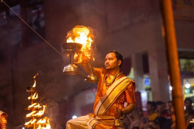 Varanasi, Uttar Pradesh, Hindistan - 20 Kasım 2022: Ganga aarti, Dashashwamedh ghat 'ında geleneksel Hint ayinleriyle akşam üzeri genç rahibin kutsal nehir çetelerini sergilediği portre.