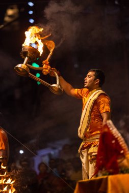 Varanasi, Uttar Pradesh, Hindistan - 20 Kasım 2022: Ganga aarti, Dashashwamedh ghat 'ında geleneksel Hint ayinleriyle akşam üzeri genç rahibin kutsal nehir çetelerini sergilediği portre.