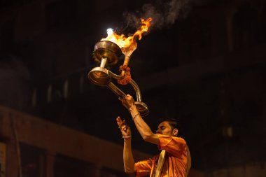 Varanasi, Uttar Pradesh, Hindistan - 20 Kasım 2022: Ganga aarti, Dashashwamedh ghat 'ında geleneksel Hint ayinleriyle akşam üzeri genç rahibin kutsal nehir çetelerini sergilediği portre.