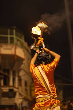 Varanasi, Uttar Pradesh, Hindistan - 20 Kasım 2022: Ganga aarti, Dashashwamedh ghat 'ında geleneksel Hint ayinleriyle akşam üzeri genç rahibin kutsal nehir çetelerini sergilediği portre.