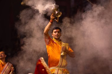 Varanasi, Uttar Pradesh, Hindistan - 20 Kasım 2022: Ganga aarti, Dashashwamedh ghat 'ında geleneksel Hint ayinleriyle akşam üzeri genç rahibin kutsal nehir çetelerini sergilediği portre.