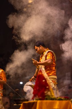 Varanasi, Uttar Pradesh, Hindistan - 20 Kasım 2022: Ganga aarti, Dashashwamedh ghat 'ında geleneksel Hint ayinleriyle akşam üzeri genç rahibin kutsal nehir çetelerini sergilediği portre.