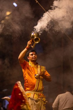 Varanasi, Uttar Pradesh, Hindistan - 20 Kasım 2022: Ganga aarti, Dashashwamedh ghat 'ında geleneksel Hint ayinleriyle akşam üzeri genç rahibin kutsal nehir çetelerini sergilediği portre.