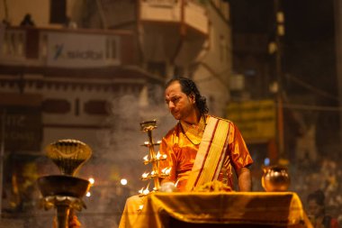 Varanasi, Uttar Pradesh, Hindistan - 20 Kasım 2022: Ganga aarti, Dashashwamedh ghat 'ında geleneksel Hint ayinleriyle akşam üzeri genç rahibin kutsal nehir çetelerini sergilediği portre.