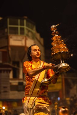 Varanasi, Uttar Pradesh, Hindistan - 20 Kasım 2022: Ganga aarti, Dashashwamedh ghat 'ında geleneksel Hint ayinleriyle akşam üzeri genç rahibin kutsal nehir çetelerini sergilediği portre.