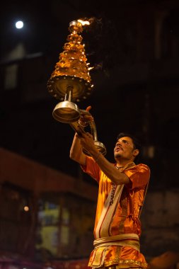 Varanasi, Uttar Pradesh, Hindistan - 20 Kasım 2022: Ganga aarti, Dashashwamedh ghat 'ında geleneksel Hint ayinleriyle akşam üzeri genç rahibin kutsal nehir çetelerini sergilediği portre.