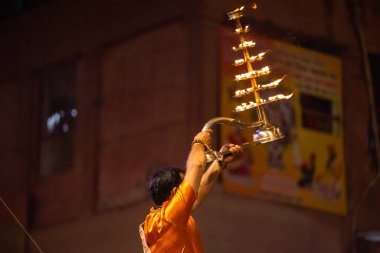 Varanasi, Uttar Pradesh, Hindistan - 20 Kasım 2022: Ganga aarti, Dashashwamedh ghat 'ında geleneksel Hint ayinleriyle akşam üzeri genç rahibin kutsal nehir çetelerini sergilediği portre.