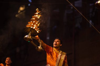 Varanasi, Uttar Pradesh, Hindistan - 20 Kasım 2022: Ganga aarti, Dashashwamedh ghat 'ında geleneksel Hint ayinleriyle akşam üzeri genç rahibin kutsal nehir çetelerini sergilediği portre.