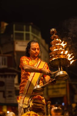 Varanasi, Uttar Pradesh, Hindistan - 20 Kasım 2022: Ganga aarti, Dashashwamedh ghat 'ında geleneksel Hint ayinleriyle akşam üzeri genç rahibin kutsal nehir çetelerini sergilediği portre.