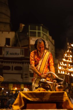 Varanasi, Uttar Pradesh, Hindistan - 20 Kasım 2022: Ganga aarti, Dashashwamedh ghat 'ında geleneksel Hint ayinleriyle akşam üzeri genç rahibin kutsal nehir çetelerini sergilediği portre.