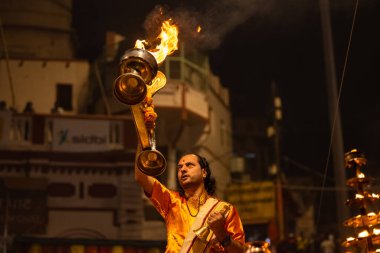 Varanasi, Uttar Pradesh, Hindistan - 20 Kasım 2022: Ganga aarti, Dashashwamedh ghat 'ında geleneksel Hint ayinleriyle akşam üzeri genç rahibin kutsal nehir çetelerini sergilediği portre.