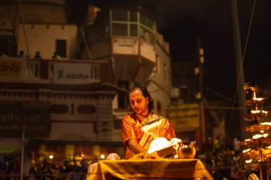 Varanasi, Uttar Pradesh, Hindistan - 20 Kasım 2022: Ganga aarti, Dashashwamedh ghat 'ında geleneksel Hint ayinleriyle akşam üzeri genç rahibin kutsal nehir çetelerini sergilediği portre.