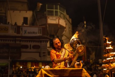 Varanasi, Uttar Pradesh, Hindistan - 20 Kasım 2022: Ganga aarti, Dashashwamedh ghat 'ında geleneksel Hint ayinleriyle akşam üzeri genç rahibin kutsal nehir çetelerini sergilediği portre.