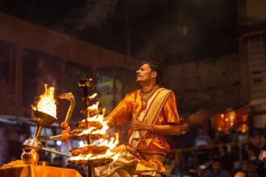 Varanasi, Uttar Pradesh, Hindistan - 20 Kasım 2022: Ganga aarti, Dashashwamedh ghat 'ında geleneksel Hint ayinleriyle akşam üzeri genç rahibin kutsal nehir çetelerini sergilediği portre.