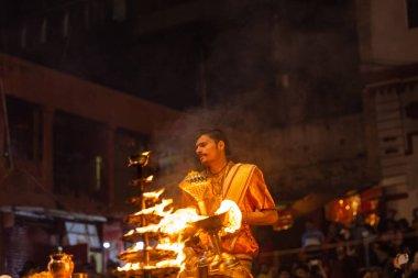 Varanasi, Uttar Pradesh, Hindistan - 20 Kasım 2022: Ganga aarti, Dashashwamedh ghat 'ında geleneksel Hint ayinleriyle akşam üzeri genç rahibin kutsal nehir çetelerini sergilediği portre.