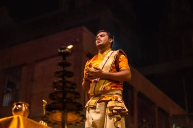 Varanasi, Uttar Pradesh, Hindistan - 20 Kasım 2022: Ganga aarti, Dashashwamedh ghat 'ında geleneksel Hint ayinleriyle akşam üzeri genç rahibin kutsal nehir çetelerini sergilediği portre.