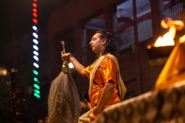 Varanasi, Uttar Pradesh, Hindistan - 20 Kasım 2022: Ganga aarti, Dashashwamedh ghat 'ında geleneksel Hint ayinleriyle akşam üzeri genç rahibin kutsal nehir çetelerini sergilediği portre.