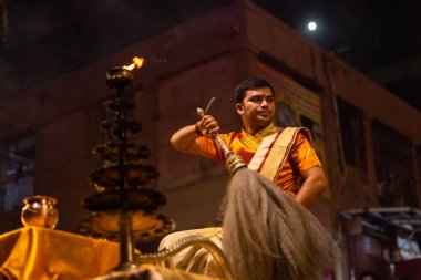 Varanasi, Uttar Pradesh, Hindistan - 20 Kasım 2022: Ganga aarti, Dashashwamedh ghat 'ında geleneksel Hint ayinleriyle akşam üzeri genç rahibin kutsal nehir çetelerini sergilediği portre.