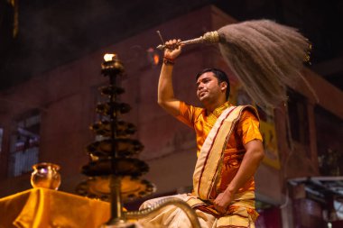 Varanasi, Uttar Pradesh, Hindistan - 20 Kasım 2022: Ganga aarti, Dashashwamedh ghat 'ında geleneksel Hint ayinleriyle akşam üzeri genç rahibin kutsal nehir çetelerini sergilediği portre.