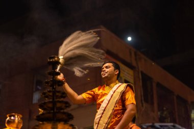 Varanasi, Uttar Pradesh, Hindistan - 20 Kasım 2022: Ganga aarti, Dashashwamedh ghat 'ında geleneksel Hint ayinleriyle akşam üzeri genç rahibin kutsal nehir çetelerini sergilediği portre.