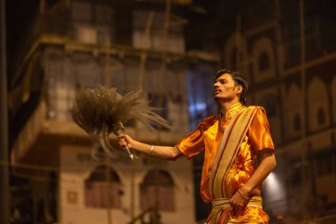 Varanasi, Uttar Pradesh, Hindistan - 20 Kasım 2022: Ganga aarti, Dashashwamedh ghat 'ında geleneksel Hint ayinleriyle akşam üzeri genç rahibin kutsal nehir çetelerini sergilediği portre.