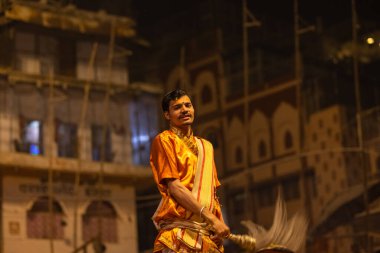 Varanasi, Uttar Pradesh, Hindistan - 20 Kasım 2022: Ganga aarti, Dashashwamedh ghat 'ında geleneksel Hint ayinleriyle akşam üzeri genç rahibin kutsal nehir çetelerini sergilediği portre.