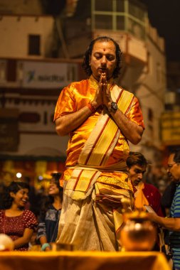 Varanasi, Uttar Pradesh, Hindistan - 20 Kasım 2022: Ganga aarti, Dashashwamedh ghat 'ında geleneksel Hint ayinleriyle akşam üzeri genç rahibin kutsal nehir çetelerini sergilediği portre.
