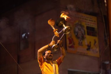 Varanasi, Uttar Pradesh, Hindistan - 20 Kasım 2022: Ganga aarti, Dashashwamedh ghat 'ında geleneksel Hint ayinleriyle akşam üzeri genç rahibin kutsal nehir çetelerini sergilediği portre.