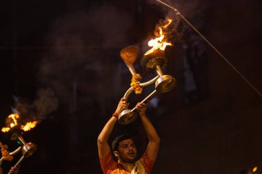 Varanasi, Uttar Pradesh, Hindistan - 20 Kasım 2022: Ganga aarti, Dashashwamedh ghat 'ında geleneksel Hint ayinleriyle akşam üzeri genç rahibin kutsal nehir çetelerini sergilediği portre.