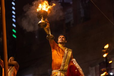 Varanasi, Uttar Pradesh, Hindistan - 20 Kasım 2022: Ganga aarti, Dashashwamedh ghat 'ında geleneksel Hint ayinleriyle akşam üzeri genç rahibin kutsal nehir çetelerini sergilediği portre.