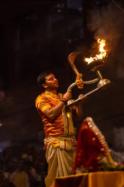 Varanasi, Uttar Pradesh, Hindistan - 20 Kasım 2022: Ganga aarti, Dashashwamedh ghat 'ında geleneksel Hint ayinleriyle akşam üzeri genç rahibin kutsal nehir çetelerini sergilediği portre.