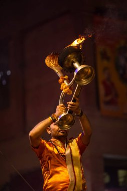 Varanasi, Uttar Pradesh, Hindistan - 20 Kasım 2022: Ganga aarti, Dashashwamedh ghat 'ında geleneksel Hint ayinleriyle akşam üzeri genç rahibin kutsal nehir çetelerini sergilediği portre.