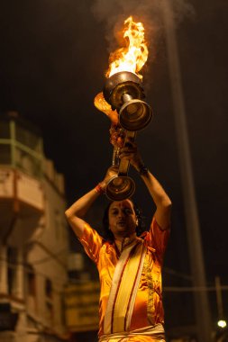 Varanasi, Uttar Pradesh, Hindistan - 20 Kasım 2022: Ganga aarti, Dashashwamedh ghat 'ında geleneksel Hint ayinleriyle akşam üzeri genç rahibin kutsal nehir çetelerini sergilediği portre.