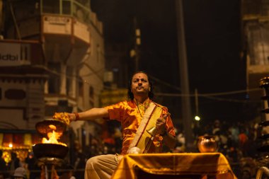 Varanasi, Uttar Pradesh, Hindistan - 20 Kasım 2022: Ganga aarti, Dashashwamedh ghat 'ında geleneksel Hint ayinleriyle akşam üzeri genç rahibin kutsal nehir çetelerini sergilediği portre.