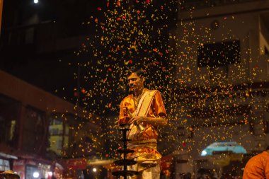 Varanasi, Uttar Pradesh, Hindistan - 20 Kasım 2022: Ganga aarti, Dashashwamedh ghat 'ında geleneksel Hint ayinleriyle akşam üzeri genç rahibin kutsal nehir çetelerini sergilediği portre.