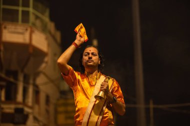 Varanasi, Uttar Pradesh, Hindistan - 20 Kasım 2022: Ganga aarti, Dashashwamedh ghat 'ında geleneksel Hint ayinleriyle akşam üzeri genç rahibin kutsal nehir çetelerini sergilediği portre.