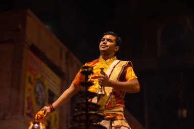 Varanasi, Uttar Pradesh, Hindistan - 20 Kasım 2022: Ganga aarti, Dashashwamedh ghat 'ında geleneksel Hint ayinleriyle akşam üzeri genç rahibin kutsal nehir çetelerini sergilediği portre.