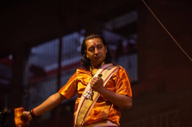 Varanasi, Uttar Pradesh, Hindistan - 20 Kasım 2022: Ganga aarti, Dashashwamedh ghat 'ında geleneksel Hint ayinleriyle akşam üzeri genç rahibin kutsal nehir çetelerini sergilediği portre.