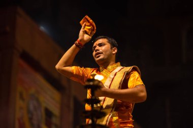 Varanasi, Uttar Pradesh, Hindistan - 20 Kasım 2022: Ganga aarti, Dashashwamedh ghat 'ında geleneksel Hint ayinleriyle akşam üzeri genç rahibin kutsal nehir çetelerini sergilediği portre.