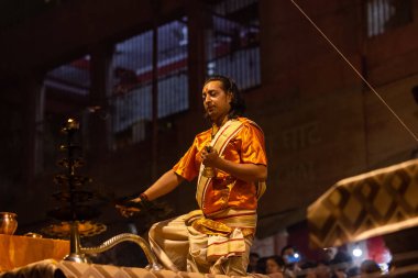 Varanasi, Uttar Pradesh, Hindistan - 20 Kasım 2022: Ganga aarti, Dashashwamedh ghat 'ında geleneksel Hint ayinleriyle akşam üzeri genç rahibin kutsal nehir çetelerini sergilediği portre.