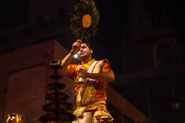 Varanasi, Uttar Pradesh, Hindistan - 20 Kasım 2022: Ganga aarti, Dashashwamedh ghat 'ında geleneksel Hint ayinleriyle akşam üzeri genç rahibin kutsal nehir çetelerini sergilediği portre.